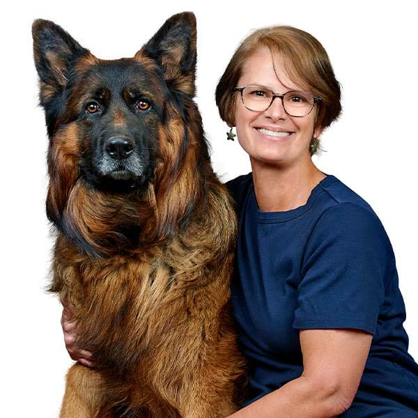 Hospital Director, Lauren St. Claire, holding her giant German shepherd mixed breed dog while smiling