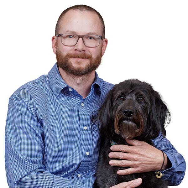 Board-Certified Small Animal Internal Medicine Specialist and Medical Director, Daniel Hume, hugging his black fluffy dog